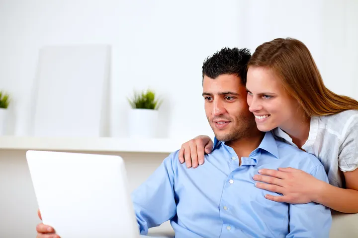 Una pareja revisa sus seguros en un computador portátil desde su casa.